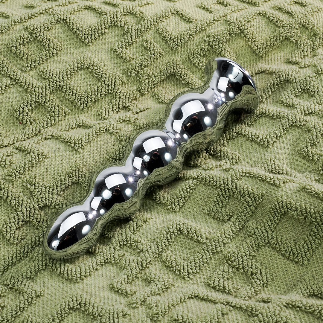 Shiny silver Gude butt plug on green towel