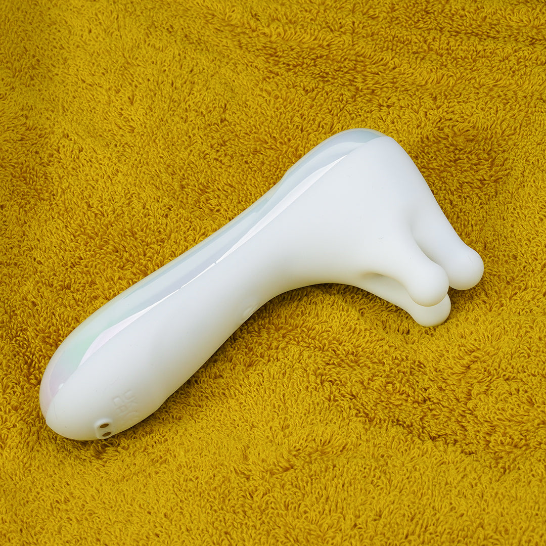 White nipple vibrator with three heads on yellow towel