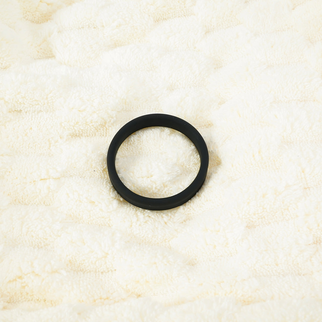 Black silicone cock ring on a white fluffy surface.